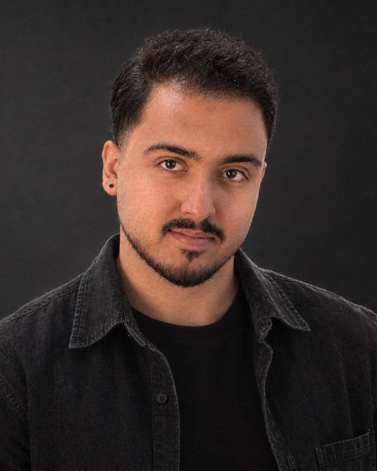 Portrait of Ryan Yarali in a dark denim shirt against a charcoal backdrop